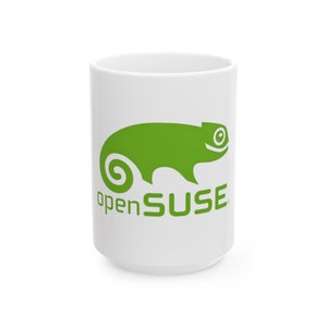 Könnte beinhalten: Weißer Keramikbecher mit grünem Chamäleon-Logo und dem Text "openSUSE". Der Becher ist zylindrisch und hat ein schlichtes Design. Geeignet für Kaffee, Tee oder andere Getränke. Höhe ca. 12 cm.