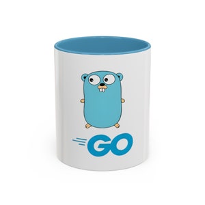 Op de afbeelding: Witte keramische mok met een blauwe rand. De mok heeft een blauwe cartoon gopher met het woord "GO" in blauw eronder.