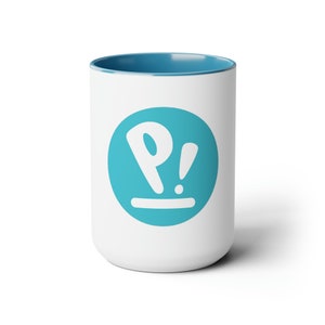 May include: White ceramic mug with a blue rim and a blue circle logo with a white "P!" inside.