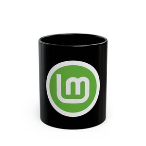 Könnte beinhalten: Eine schwarze Keramiktasse mit einem weißen Kreis und dem grünen Linux Mint-Logo.