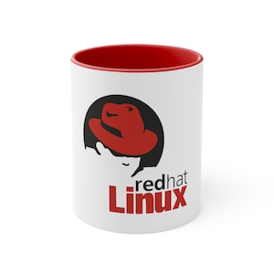 Könnte beinhalten: Weiße Keramiktasse mit rotem Rand. Die Tasse zeigt ein schwarz-rotes Logo eines roten Hutes mit dem Schatten einer Person, die den Hut trägt. Der Text "redhat Linux" ist in Rot unter dem Logo gedruckt.