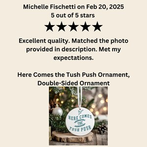 Op de afbeelding: Witte keramische ornament met de tekst "Here Comes the Tush Push" in tealblauwe letters. De ornament hangt aan een wit lint en is omringd door een groene kerstboom.