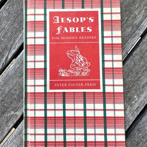 May include: A red, white, and green plaid book cover with the title "Aesop's Fables for Modern Readers" and a black and white illustration of a frog. The book is published by Peter Pauper Press.