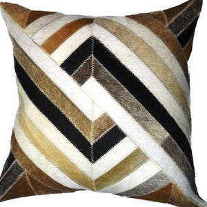May include: A square throw pillow with a geometric pattern made of brown, black, and white cowhide leather.