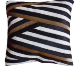 May include: A black and white striped throw pillow with brown stripes. The pillow is made of a soft, plush fabric.