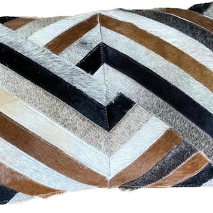 May include: A decorative cushion with a geometric pattern made of different coloured leather pieces. The cushion is made of brown, black, white, and grey leather.