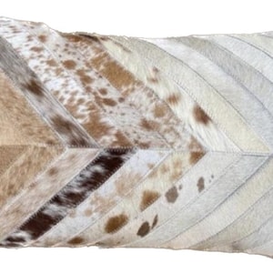 May include: A decorative pillow with a chevron pattern made from cowhide in shades of white, brown, and tan.