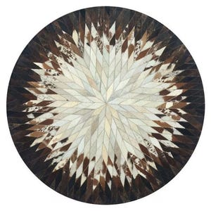 May include: A round, brown and white cowhide rug with a starburst pattern. The rug is made of many small pieces of leather sewn together.