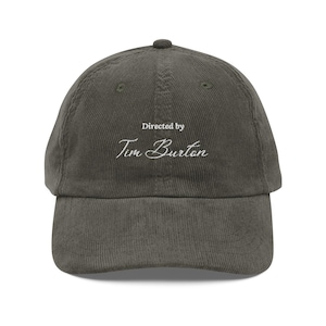 May include: A dark green corduroy baseball cap with white embroidery that reads "Directed by Tim Burton".