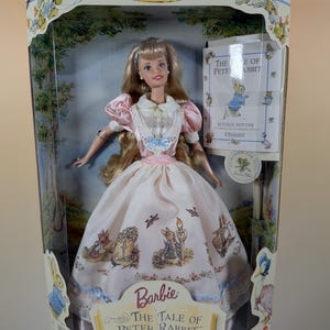 May include: A Barbie doll in a collector's edition box. The doll is dressed in a pink and white gown with illustrations from "The Tale of Peter Rabbit." The box features the text "Collector Edition" and "The Tale of Peter Rabbit."