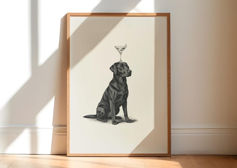 May include: A framed print featuring a black Labrador Retriever with a martini glass balanced on its head. The dog is depicted in a seated position, with a detailed pencil-style drawing. The artwork is set against a neutral background.