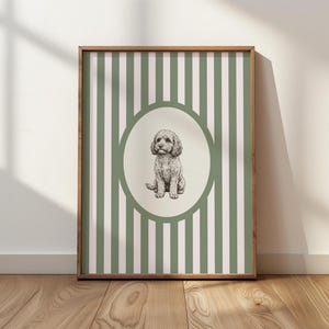 May include: A framed print featuring a seated dog illustration within an oval frame. The background has vertical stripes in green and white. The wooden frame complements the artwork, suitable for home decor.