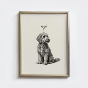 May include: A framed black and white print of a dog with a martini glass balanced on its head. The dog is a medium-sized breed with curly fur, sitting upright. The martini glass has an olive. The frame is gold.