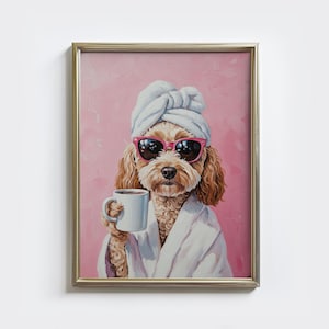 Pode incluir: Uma impressão emoldurada apresenta um poodle usando óculos de sol, uma toalha branca na cabeça e um roupão branco, segurando uma caneca de café. O fundo é rosa texturizado. A moldura é dourada.