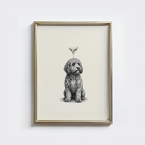 May include: A framed black and white print featuring a seated dog with a martini glass balanced on its head. The dog has curly fur and a serious expression. The martini glass has an olive. The frame is gold.
