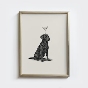 Puede incluir: Una impresión enmarcada que presenta un Labrador Retriever negro con una copa de martini equilibrada en su cabeza. El perro está sentado y la copa de martini tiene una aceituna verde. El marco es dorado.