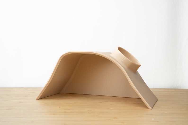 Pu&ograve; includere: Un letto per gatti in plastica beige a forma di tunnel curvo con un'apertura rotonda nella parte superiore.