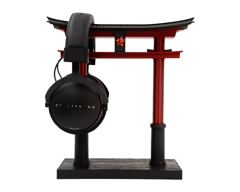 May include: Black headphones with a black stand and a red Japanese torii gate. The headphones have the text "DT 177X GO" on the side. The torii gate has the Japanese character "待" on it.