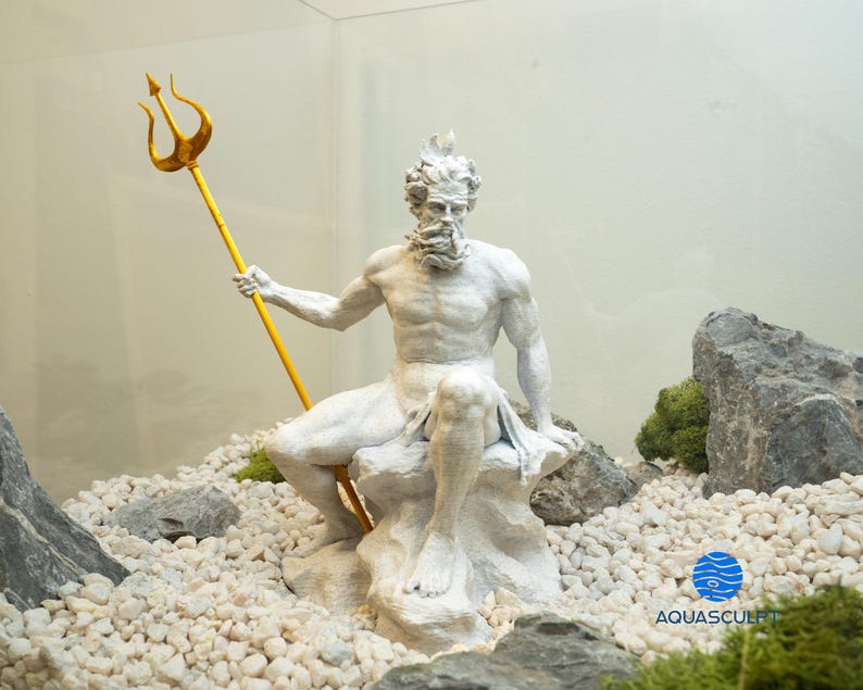 以下が含まれることがあります： 白い樹脂製のポセイドン像。ギリシャの海の神ポセイドンが、金の三叉槍を持って岩に座っている。像は白い小石と緑の苔に囲まれている。