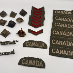 Peut inclure: Ensemble d'insignes et d'écussons militaires vintage. Comprend plusieurs badges en forme d'étoile, une petite couronne, des chevrons à rayures rouges et des écussons avec le mot "CANADA" en lettres beiges sur fond vert.