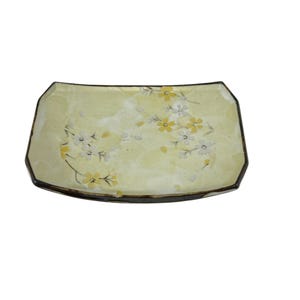 Puede incluir: Un plato de servir de cerámica amarillo claro con un borde marrón y un diseño floral con flores blancas y amarillas.