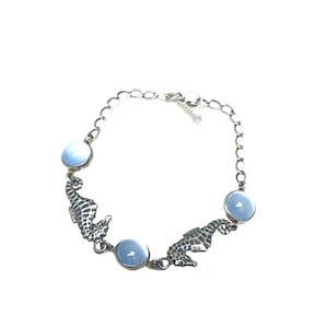 May include: Silver-toned bracelet featuring three light blue, round stones and two seahorse charms. The bracelet has a chain link design and a lobster claw clasp. A delicate piece of jewelry.