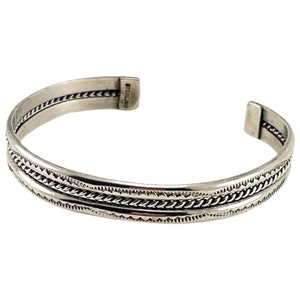 May include: A silver bracelet with a braided design and the word "STERLING" stamped on the back.