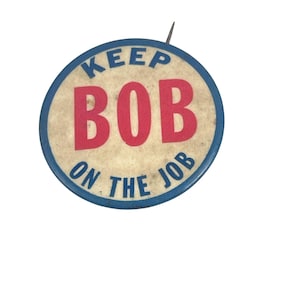 May include: A blue and white button with the text "Keep Bob on the Job" in red and blue lettering.