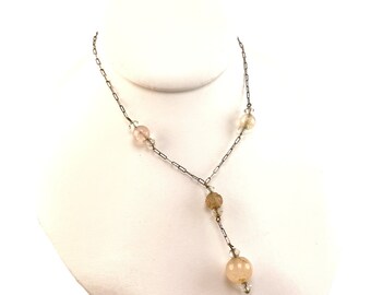 Peut inclure: Un collier délicat en chaîne argentée avec un pendentif en perles de verre rose et transparentes. Le collier présente plusieurs petites perles de verre roses et transparentes le long de la chaîne.
