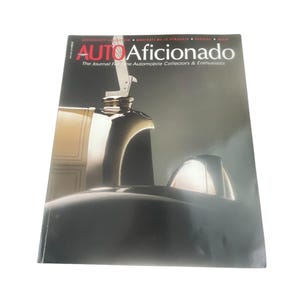 May include: A magazine cover featuring a black and silver car with the title "AUTO Aficionado" and the tagline "The Journal For Fine Automobile Collectors & Enthusiasts".