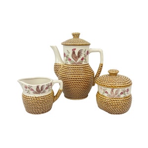 Könnte beinhalten: Ein braunes und weißes Keramik-Tee-Set mit einem Hahn-Design. Die Teekanne, die Milchkännchen und die Zuckerdose haben ein geflochtenes Korbmuster.
