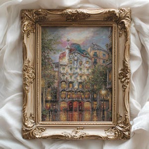 May include: A framed painting of a European city street scene. The artwork shows a building with unique architecture, lit windows, and a colourful sky. The ornate, gold-coloured frame adds a classic touch to the artwork.