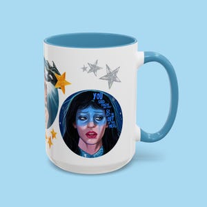 May include: White ceramic mug with a blue interior and handle. The mug features a portrait of a woman with blue face paint and the text "YOU SAID FORGIVE AND FORGET SO GET ME OUT OF THIS MESS". Decorative stars and a gold star are also on the mug.