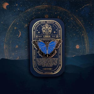 May include: A gold and blue enamel pin featuring a blue morpho butterfly with the text "LIBRA" and "BLUE MORPHO BUTTERFLY" on a black background. The pin also includes the dates "Sept 23" and "Oct 22" and a symbol of a scale.
