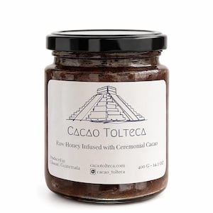 May include: A glass jar of raw honey infused with ceremonial cacao, labeled "Cacao Tolteca." The jar has a black lid and a white label with a pyramid illustration. The jar contains 14.1 oz of honey.