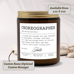 May include: A brown glass candle jar with a gold lid. The label reads "CHOREOGRAPHER" with a definition. The candle is available in 4 oz and 9 oz sizes. The label also includes the name "Julie" and details about the candle's composition.