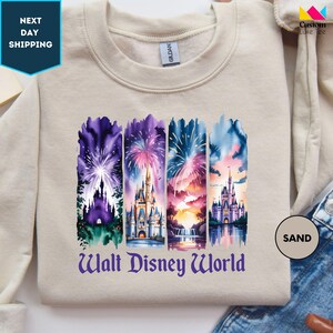 A white t-shirt with a graphic design featuring a collage of colorful castle scenes and fireworks, representing Walt Disney World.