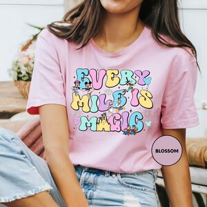 a woman wearing a pink t - shirt that says every mile's magic is