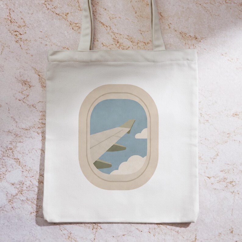 May include: White tote bag featuring an illustration of an airplane wing viewed through a window. The design includes a light blue sky, white clouds, and a beige window frame. The bag has two beige straps.