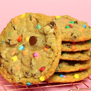 May include: A stack of chocolate chip cookies with colourful sprinkles on a wire rack. The cookies are golden brown and have a slightly crispy texture.