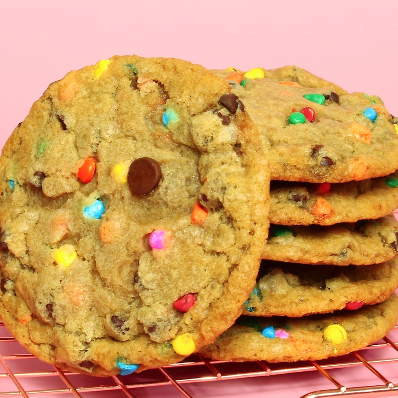 May include: A stack of chocolate chip cookies with colourful sprinkles on a wire rack. The cookies are golden brown and have a slightly crispy texture.