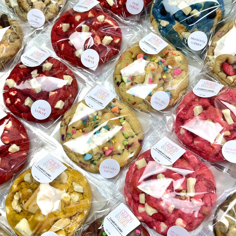 Puede incluir: Surtido de galletas decoradas en bolsas de pl&aacute;stico transparentes. Las galletas incluyen sabores de terciopelo rojo, masa para pastel de cumplea&ntilde;os, crumble de ar&aacute;ndanos y pastel de queso de fresa. Cada bolsa tiene una etiqueta con el texto "Loaded Cookie" y el nombre del sabor.