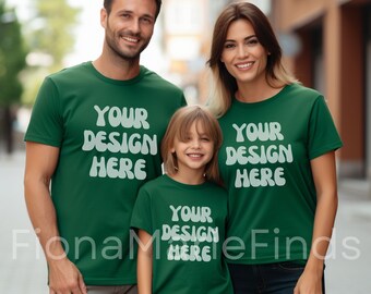 May include: Three people wearing matching green t-shirts with the text "YOUR DESIGN HERE" in white. The shirts are short-sleeved and appear to be made of a soft material. The family is smiling and standing outside.