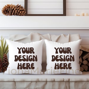 Könnte beinhalten: Zwei weiße Kissen mit dem Text "YOUR DESIGN HERE" in braunen Buchstaben auf einem weißen Sofa.