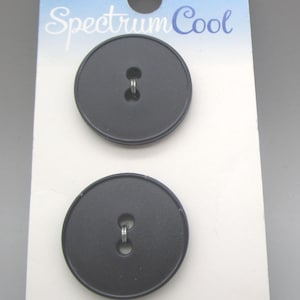 May include: Two black, round buttons with a two-hole design are displayed on a white card. The card has the text "Spectrum Cool" in a cursive font and a gradient of blue and purple at the top.