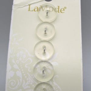 May include: A card of five clear, round buttons with metal shanks. The buttons are arranged vertically on a cream-colored card with the brand name "La mode" and the style number 4776.