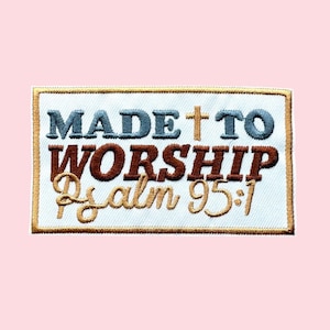 May include: Embroidered patch with the words "MADE TO WORSHIP" in blue and brown, with a gold cross and the text "Psalm 95:1" in gold script. The patch has a white background and a gold border, set against a pink backdrop.