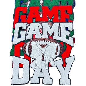 May include: A stack of five felt patches with the words "GAME DAY" in white letters with a brown football with a white bow on top. The patches are in different colours: navy blue, royal blue, green, red, and white.