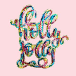 May include: A sequined "Holly Jolly" design in rainbow colors on a light pink background. The text is in a cursive font, with each letter outlined in gold sequins. The sequins create a shimmering effect.