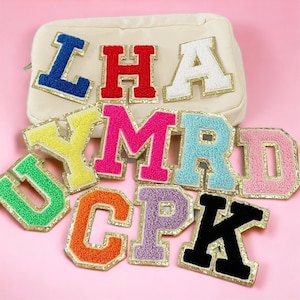 May include: A set of colorful felt letter patches with gold glitter trim. The letters are in various colors, including blue, red, white, yellow, pink, green, orange, purple, and black. The letters are arranged in a random order.